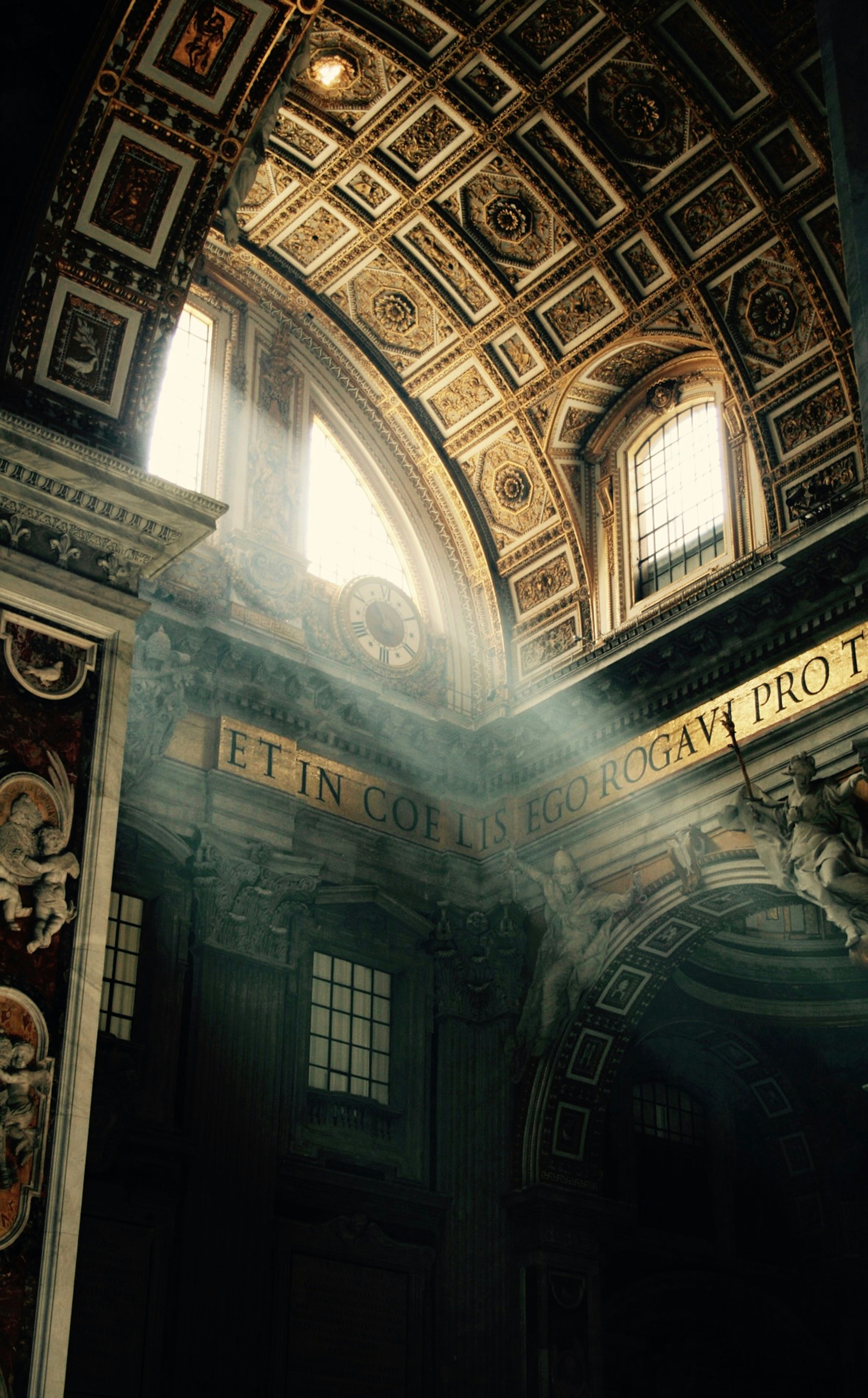 Light falling through the windows of St. Peter's Basilica, over the inscription Ego Rogavi Pro Te