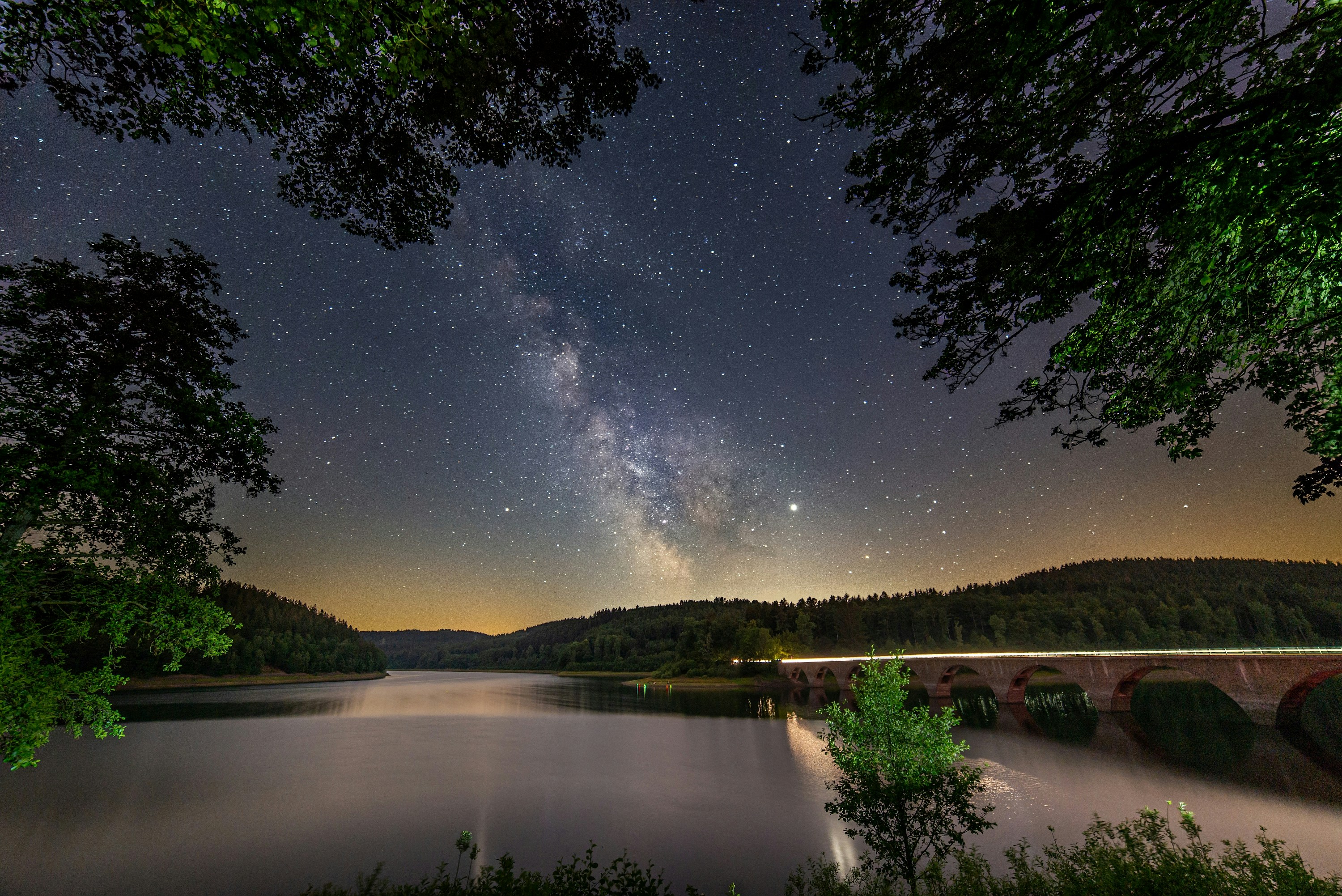 The Milky Way rising over dark mountains and water